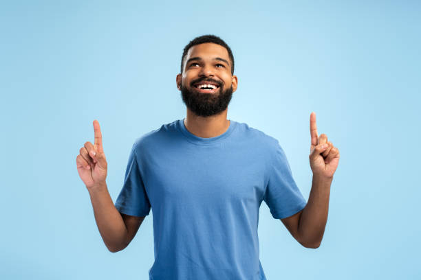istock Happy smiling African American man pointing up by his fingers while looking up over blue background 2149593385
