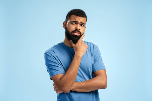 young african american man thinking concentrated about doubt, looking away - concentratie fotos stockfoto's en -beelden