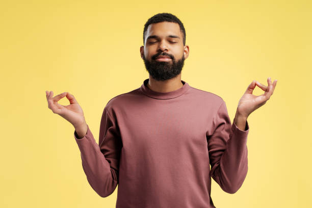 istock African American man relaxing with eyes closed, doing meditation gesture, over yellow background 2149593421