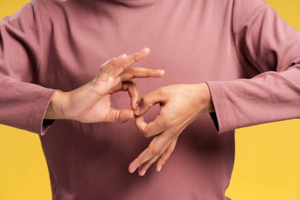 istock Close up man learning sign language to talk over yellow background in studio. Sign language concept 2149593424