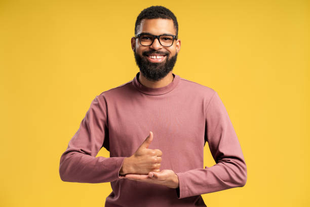 istock Smiling young African American man in eyeglasses posing in studio and learning sign language 2149593428