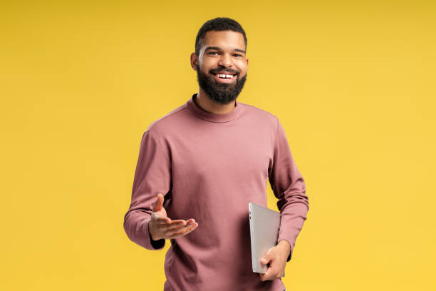 istock Smiling African American man posing in studio and holding laptop, looking at camera 2149593430