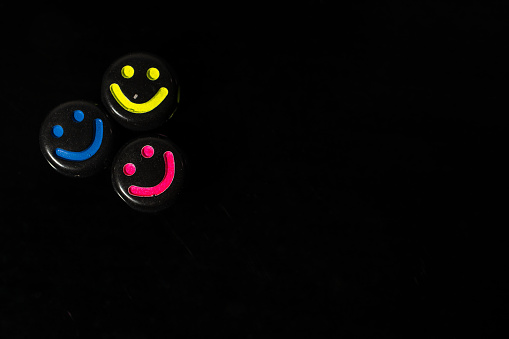 Three colorful smiley face beads on a black background. Copy space for text and advertising. Emotion beads