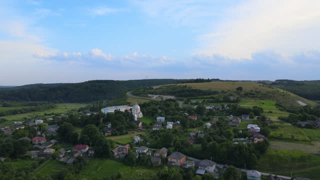 Aerial landscape view of village houses and distant green cultivated agricultural fields with growing crops