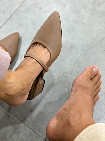 Portrait of a woman's feet wearing sandals and a man's feet waiting in the waiting room