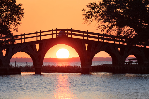 Bridge during sunset with two people witting on bridge at Historic Corolla Park in Outer Banks, North Carolina