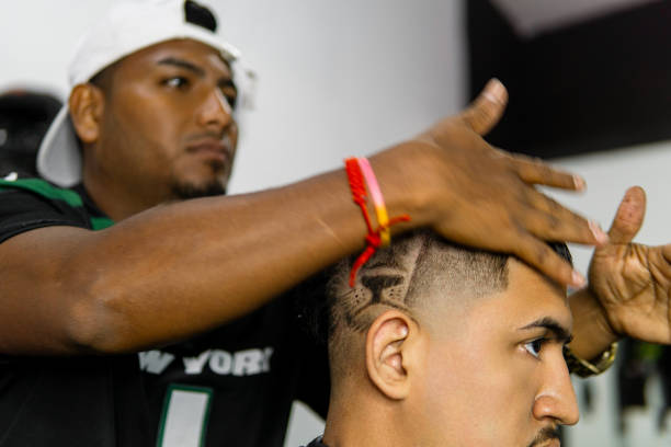 Latin man aged between 25-35 years old is make a haircut to a woman with an afro hairstyle