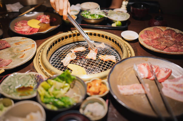 Close-up group of friend people enjoying grilling becon pork and Wagyu A5 beef Yakiniku with japanese lunch set in Kyoto Japan