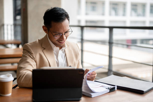 istock A confident Asian businessman is reviewing documents and working on a digital tablet. 2149606817