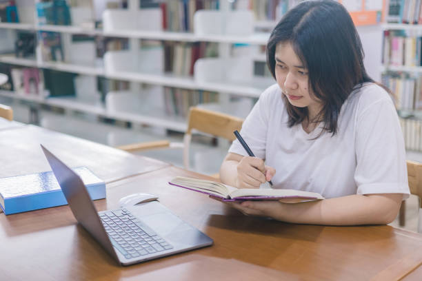 istock girl student study online with teacher, happy young woman with internet learning in library, distance education 2149608266