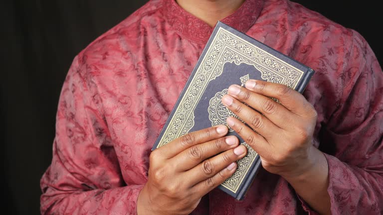 muslim man hand holding Holy book Quran with copy space