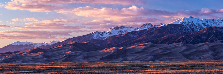 Golden hour light warms up the peaks of the Sangre de Cristo Mountains and the tops of the dunes in Great Sand Dune National Park, Colorado