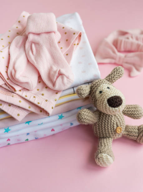 istock Baby  crocketed toy of dog  next to a stack rompers for kids 2149613463