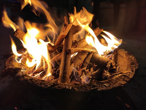 Metal fire bowl with burning wood in the yard. Safe decorative fire pit