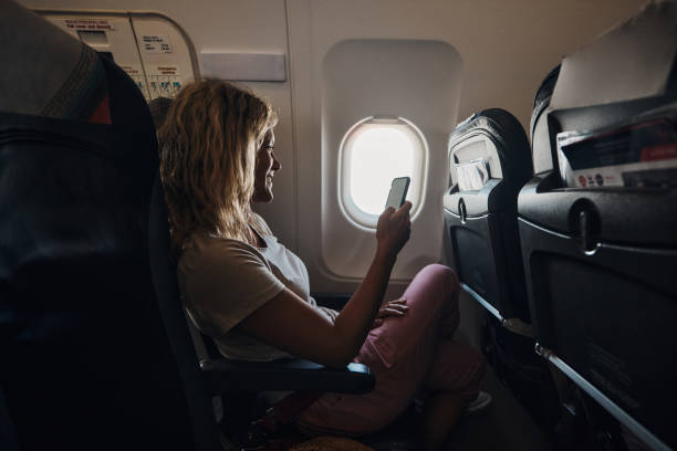 istock Happy woman using mobile phone in an airplane. 2149616017