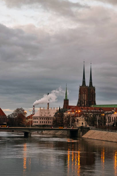 Wroclaw, Poland, February 15, 2024: A river flows through a bustling city, bordered by towering skyscrapers and high-rise buildings. The water cuts through the urban landscape, showcasing the contrast between nature and man-made structures.