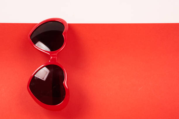 Heart shaped sunglasses and red background Copy Space. High quality photo