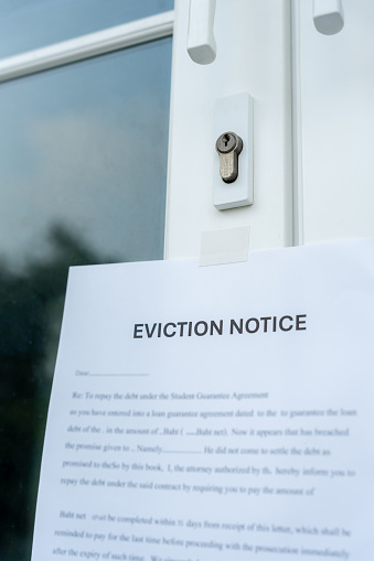 document with the text eviction notice, Civil servant sticks a notice of eviction of the tenants hangs on the door of the house, debt, property, loan, agent, bankruptcy, dispossess, problem