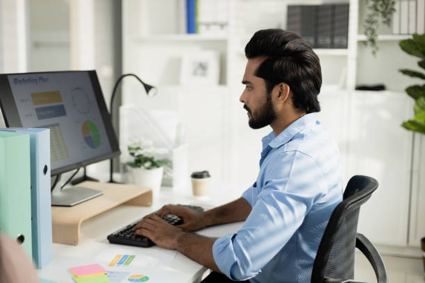 istock Indian male office worker, Working on analyzing statistics charts, Accounting officer work financial graphs with computer, HR officers make presentations for employees in organization. 2149619916