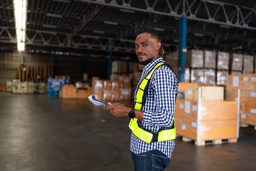 Portrait of male staff with holding clipboard working in warehouse, Industrial and industrial workers concept.