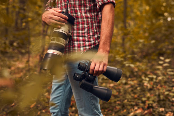istock Man using binoculars and camera for birdwatching and other observing animals in nature. 2149620860