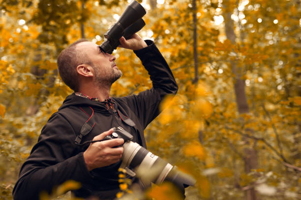 istock Man using binoculars and camera for birdwatching and other observing animals in nature. 2149620876