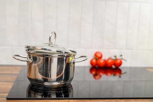 A steel pot with a lid stands on the induction hob in the kitchen