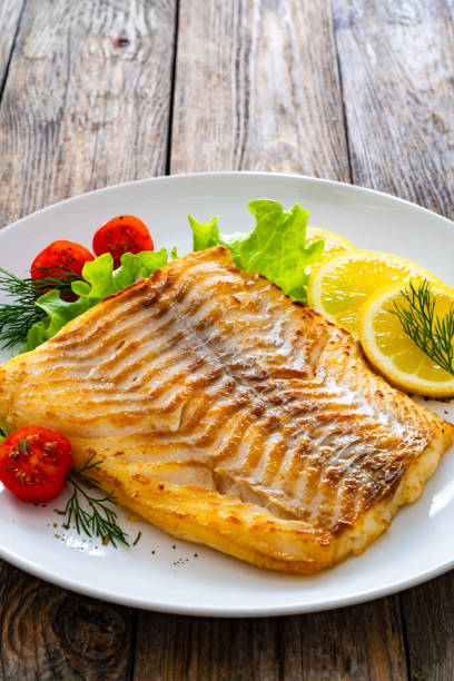 istock Fried cod fillet and fresh vegetables on wooden table 2149621356