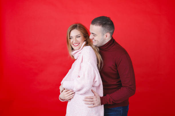 istock Young man holding his girlfriend from behind, she is smiling at camera, both wearing turtleneck shirts 2149622249