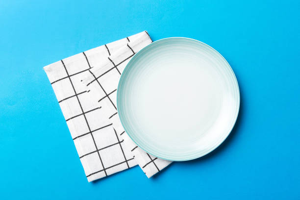istock Top view on colored background empty round blue plate on tablecloth for food. Empty dish on napkin with space for your design 2149622407