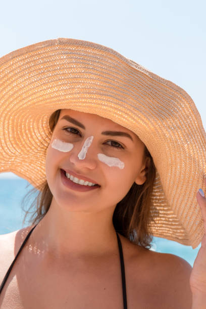 istock Smiling woman in hat is applying sunscreen on her face. Indian style 2149622435