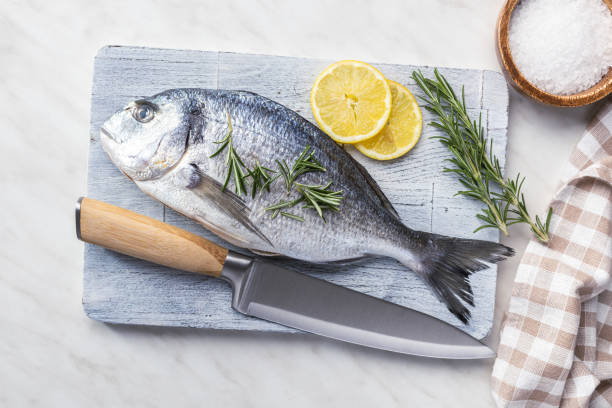 istock Fresh sea bream fish on cutting board on kitchen table. 2149622890