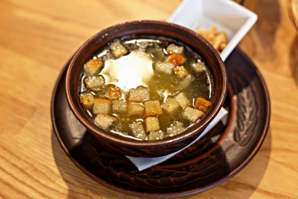 Clay bowl of fresh, delicious chicken broth or soup with crispy croutons. Homemade food that fills with warmth and nutrition. Restaurant menu