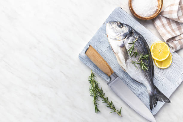 istock Fresh sea bream fish on cutting board on kitchen table. 2149623087