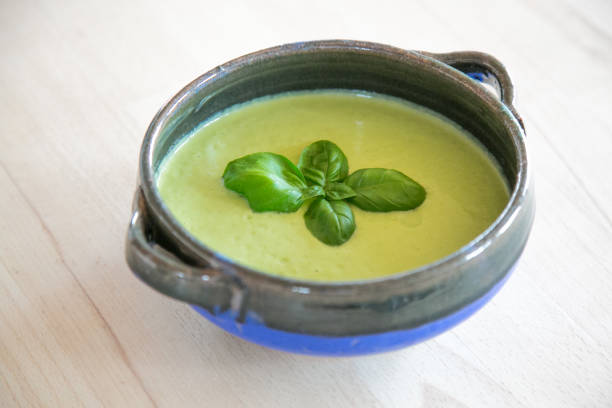 Creamy green soup decorated with basil leaves