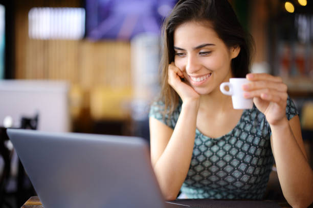 istock Happy woman checking laptop and drinking coffee in a bar 2149626149