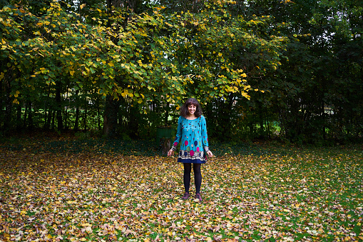 a girl in a dress with balloons is playing in the autumn garden