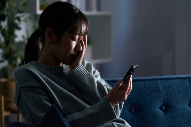 A depressed woman looking at her smartphone