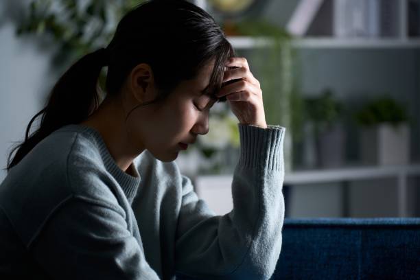 istock A woman holding her head in a dark room 2149628230