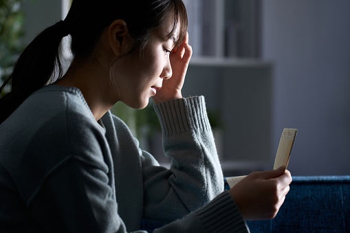 A depressed woman looking at her passbook in a dark room