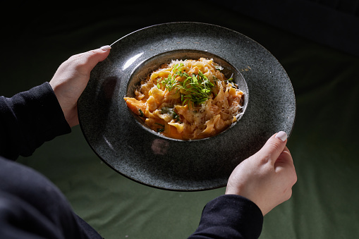 pasta on a dark plate in hands, top view