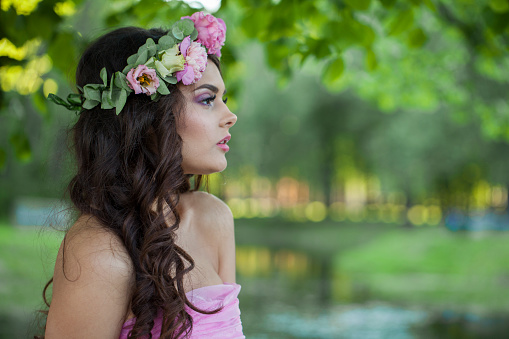 Pretty young adult lady with with long hair, make-up and pink flower in spring park. Beauty woman portrait