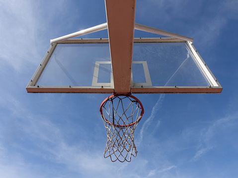 Basketball hoop with net from below on an outdoor court with sky background