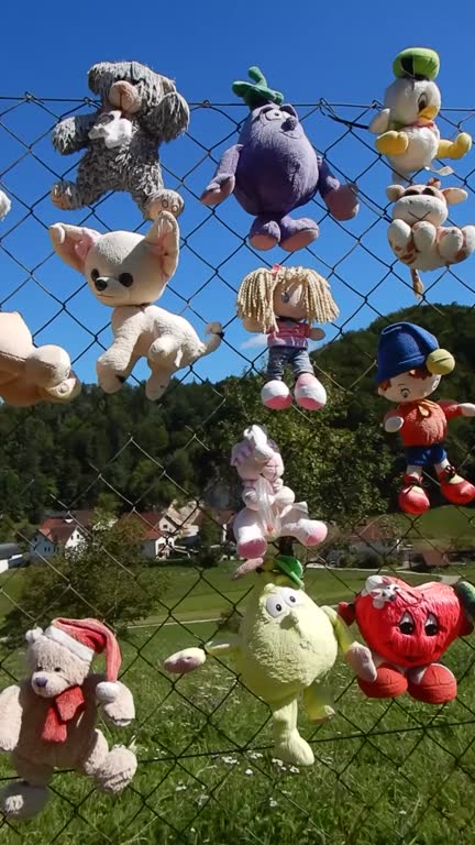 Plush Toys attached to a wire fence by the road, as a final greeting. Innovative fence decoration.