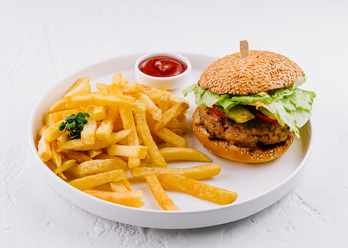 Juicy hamburger paired with golden fries and a dollop of ketchup on a clean white background