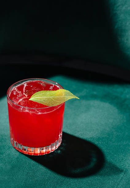 istock Refreshing red cocktail with lime garnish on green velvet 2149631555