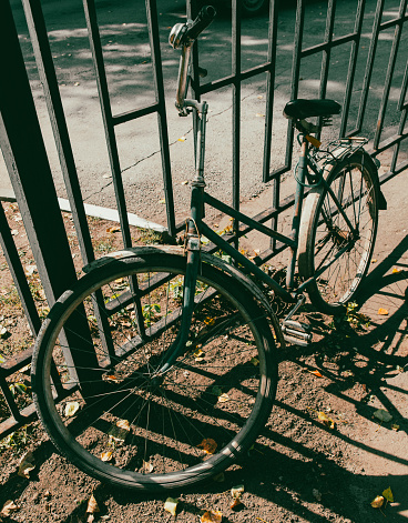 Old retro bicycle near a metal fence.
