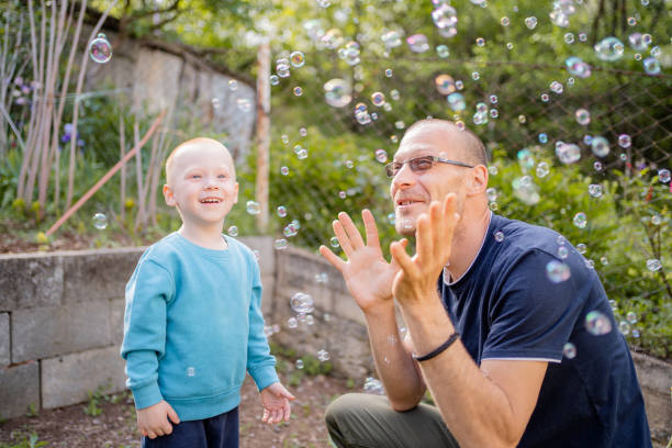 Happy father and his little son playing with soap bubbles. They enjoy playing together.