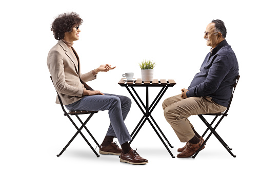 Young man sitting in a cafe and talking to a mature man isolated on white background