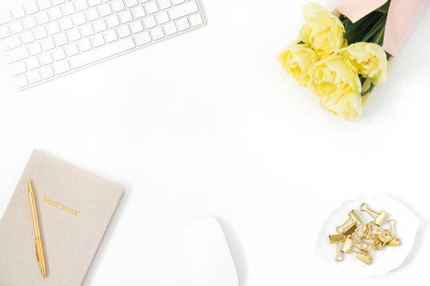 istock A woman's workspace, working at home or in the office. Copy space for a blogger: keyboard, a bunch of yellow tulips, paper clips on a plate, and a Notepad with a pen 2149632514